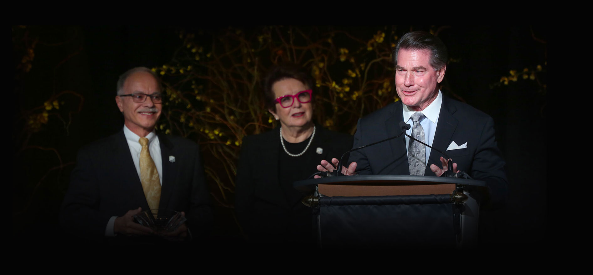 Billie Jean King, President Covino and Steve Garvey standing together at a podium.