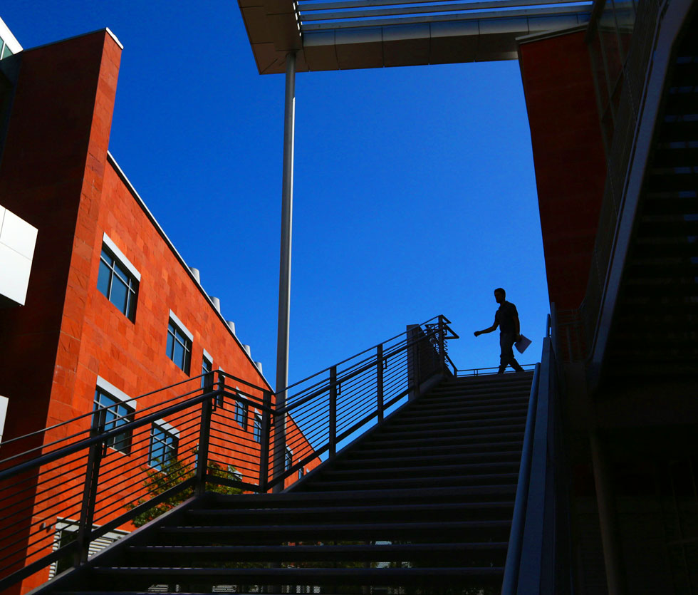 Person walking down staircase of La Kretz Hall with a vibrant blue sky behind them. Person walking down staircase of La Kretz Hall with a vibrant blue sky behind them.