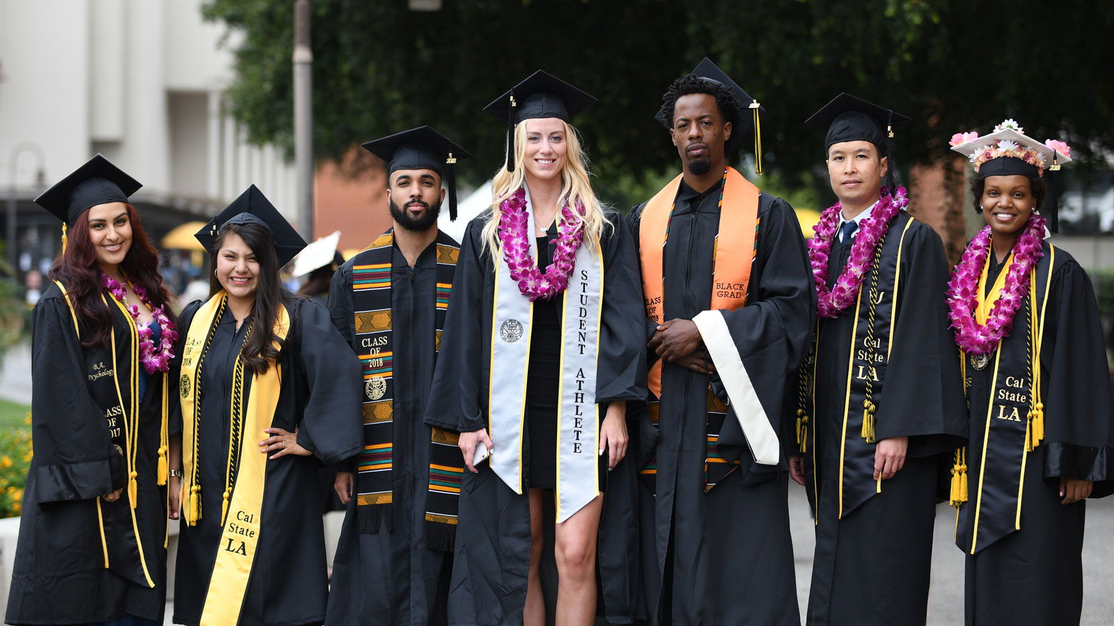 Cal State LA graduates posing with their caps and gowns Cal State LA graduates posing with their caps and gowns