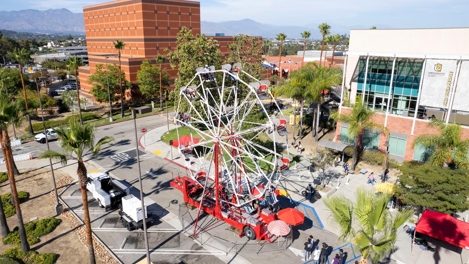 A Ferris wheel operates near the University-Student Union during Cal State LA Campus Day 2025, offering rides with campus buildings and mountains in view.