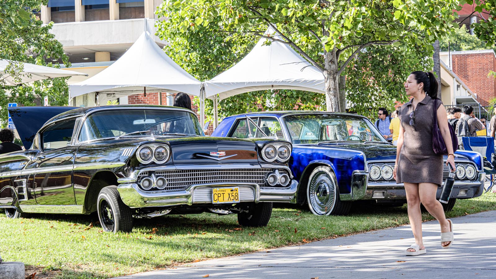 Classic cars are displayed under white tents during Cal State LA Campus Day 2025, attracting students and visitors across campus.