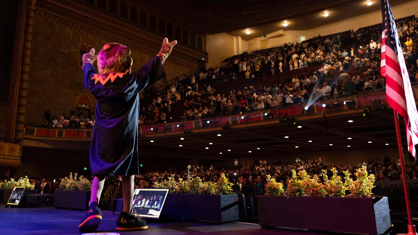 Cal State LA’s Golden Eagle mascot greets the crowd from the stage during the 2025 Commencement ceremony at the Shrine Auditorium.