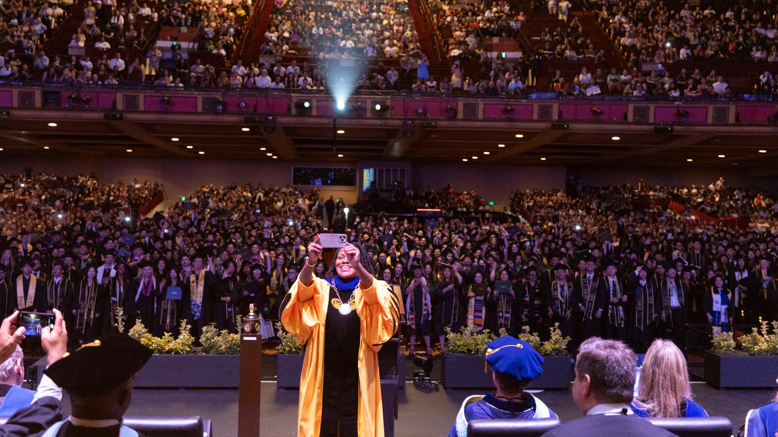 State LA President Berenecea Johnson Eanes takes a selfie with graduates and guests filling the Shrine Auditorium during the 2025 Commencement ceremony.