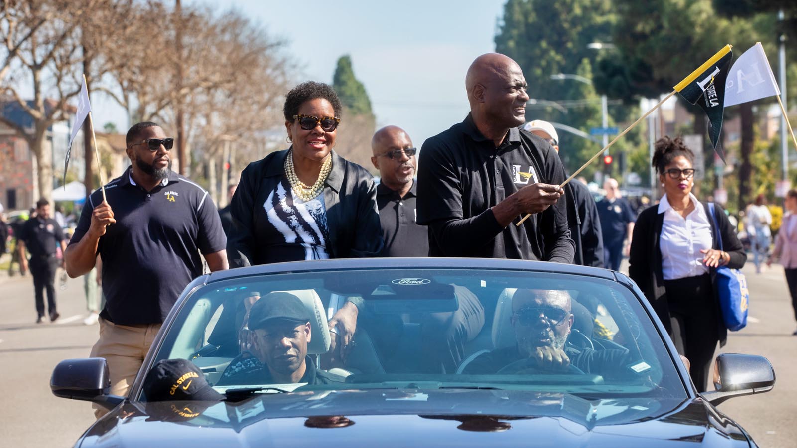 Cal State LA President Berenecea Johnson Eanes rides in a parade car with University staff and supporters waving Cal State LA flags.