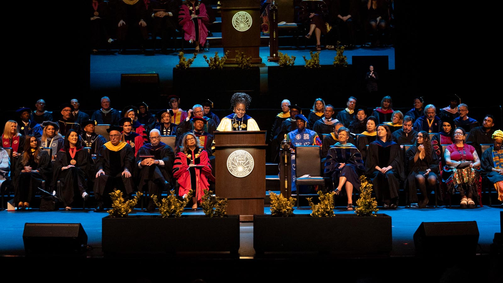 Cal State LA President Berenecea Johnson Eanes speaks on stage surrounded by faculty and administrators during the 2025 Investiture ceremony.