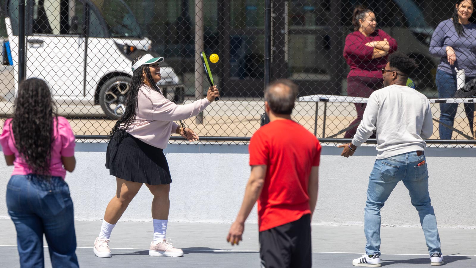 Students and staff play pickleball together on an outdoor court at Cal State LA, enjoying a sunny day of recreation and campus community engagement.