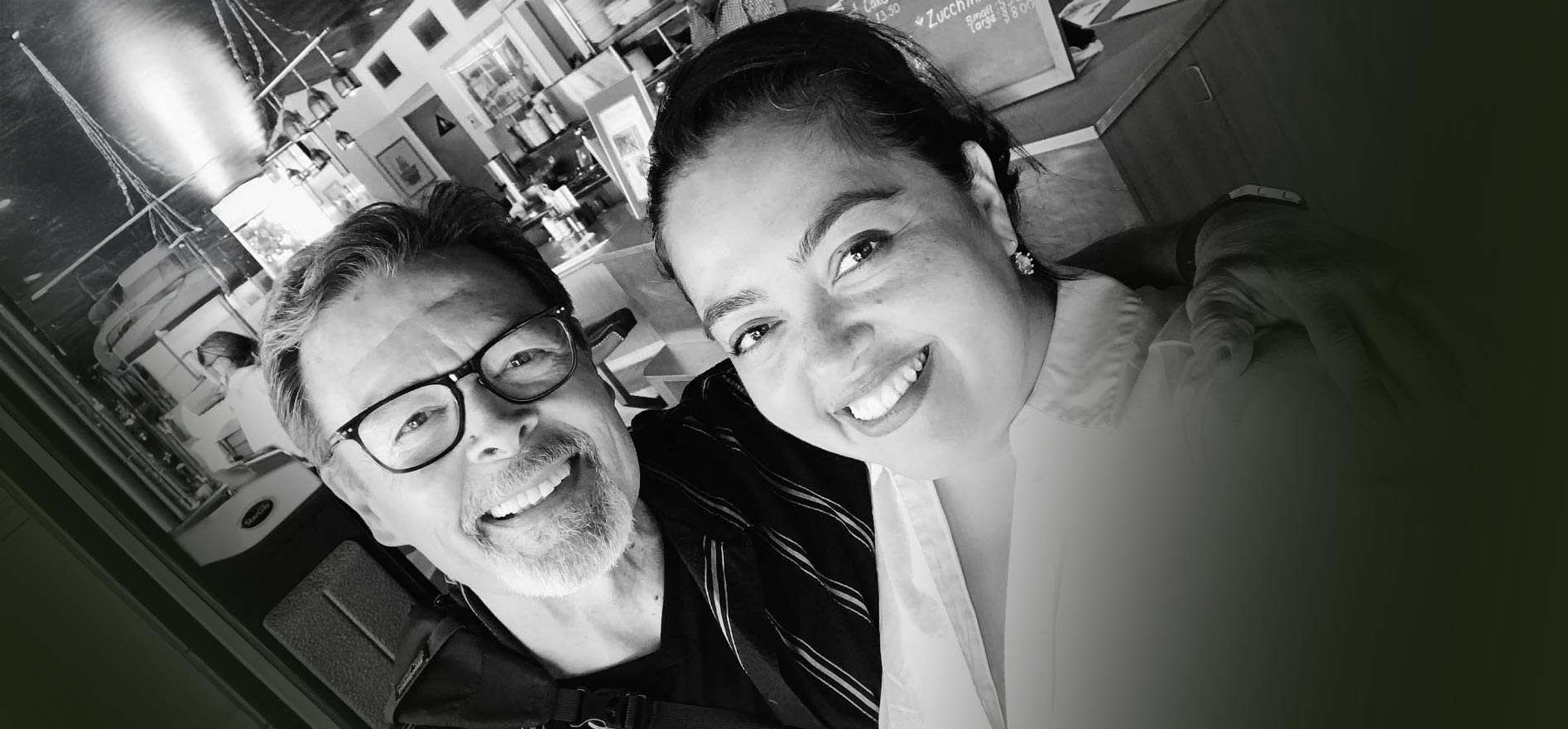 Black-and-white photo of Cal State LA alumni smiling together inside a café.