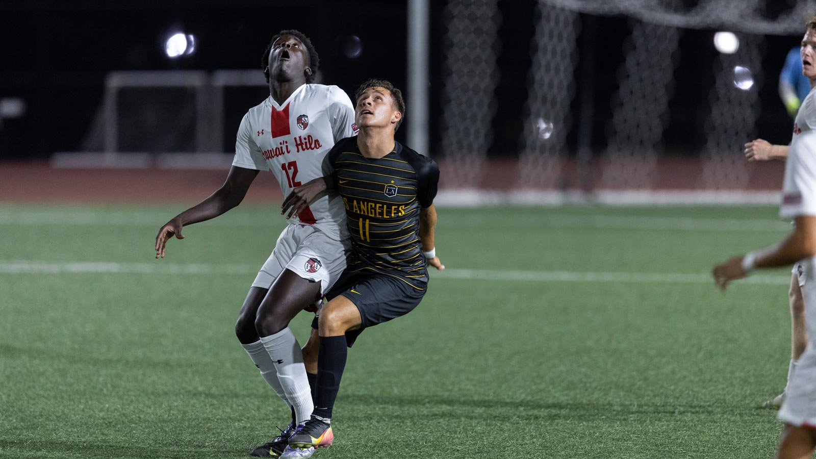 Cal State LA men’s soccer player Hunter Devlyn battles for possession against an opponent from Hawai‘i Hilo during a night match.