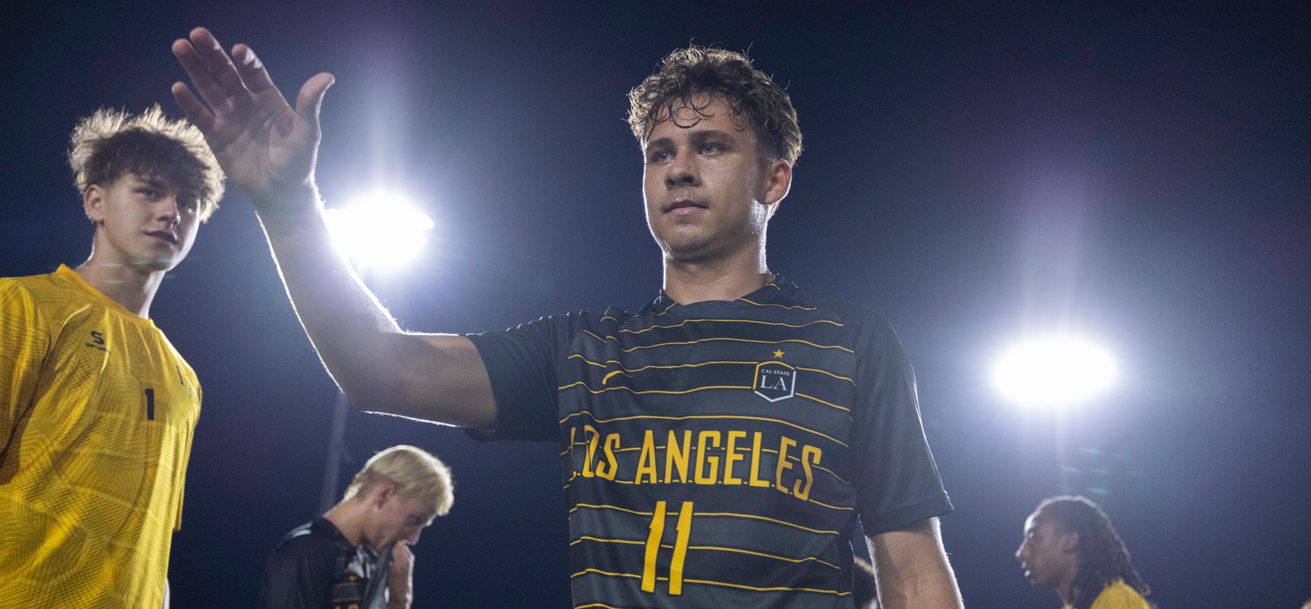 Cal State LA men’s soccer player Hunter Devlyn gestures to teammates after a game under the stadium lights.