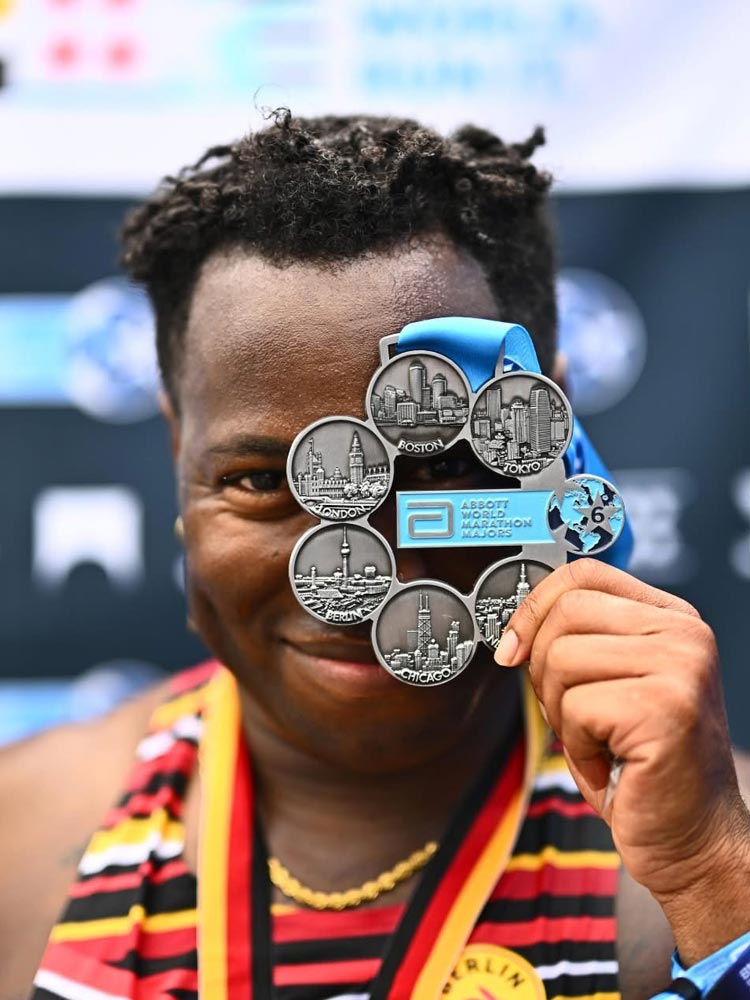 Cal State LA alumnus JT Chestnut holds up an Abbott World Marathon Majors medal featuring all six cities after completing the marathon series.
